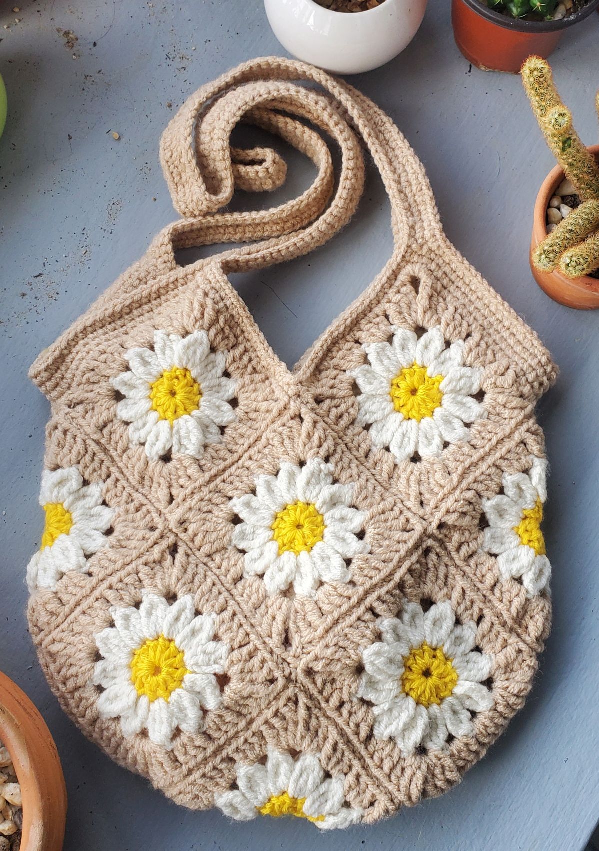 Crocheted bag with daisy flower patterns on a gray surface