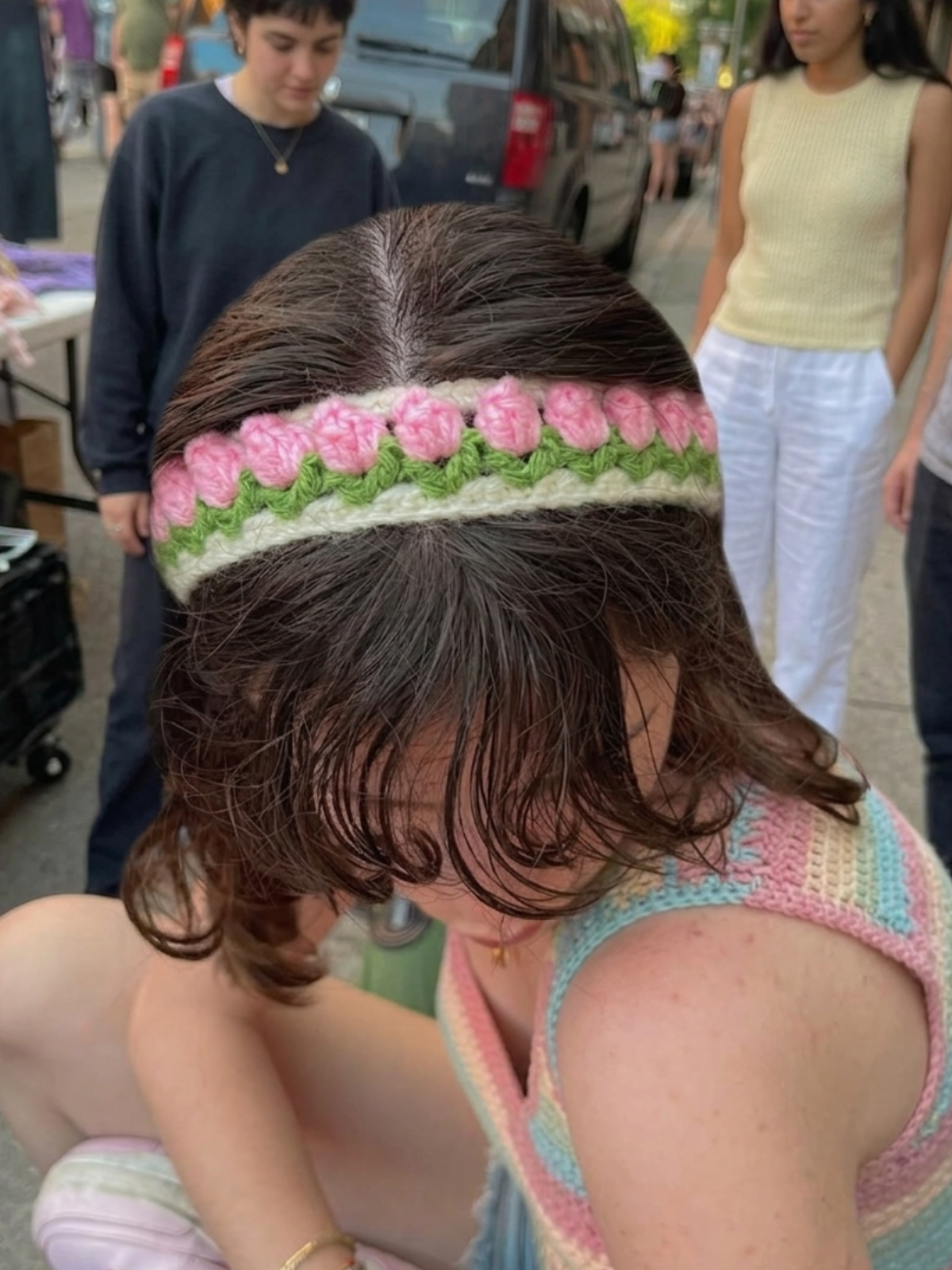 Child wearing a colorful headband with pink flowers in an outdoor setting