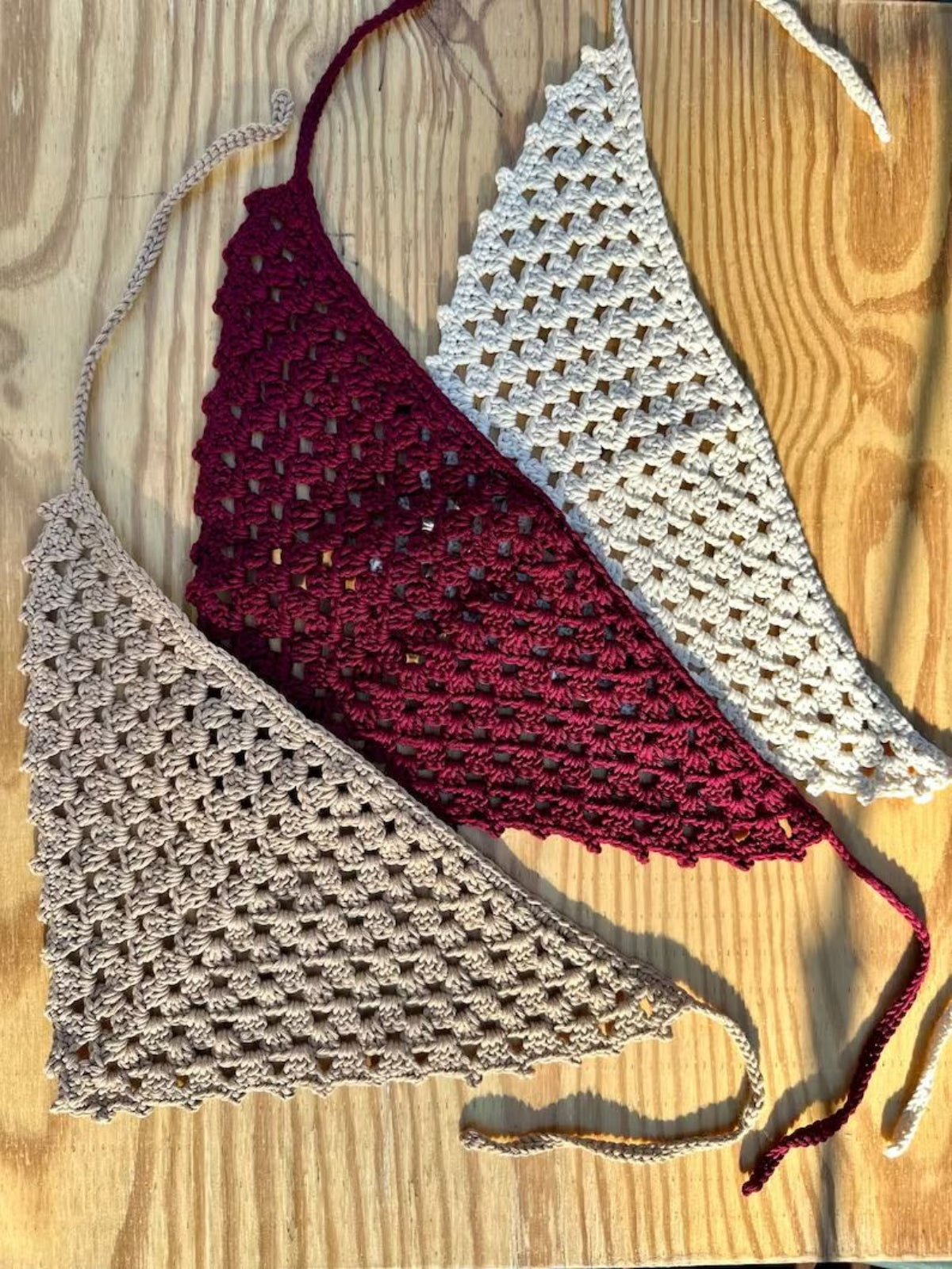 Three crocheted bandana in red and gray on a wooden surface