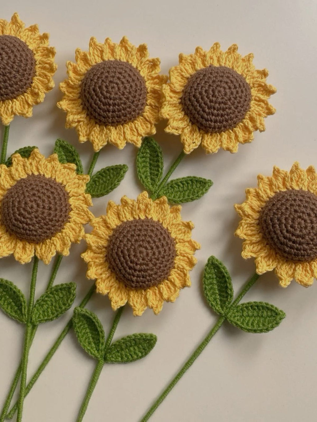 Crocheted sunflowers with brown centers and yellow petals on a beige background